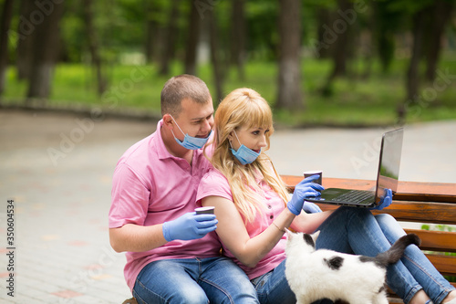 guy and girl are sitting in the park with a computer, 
coronavirus, covid