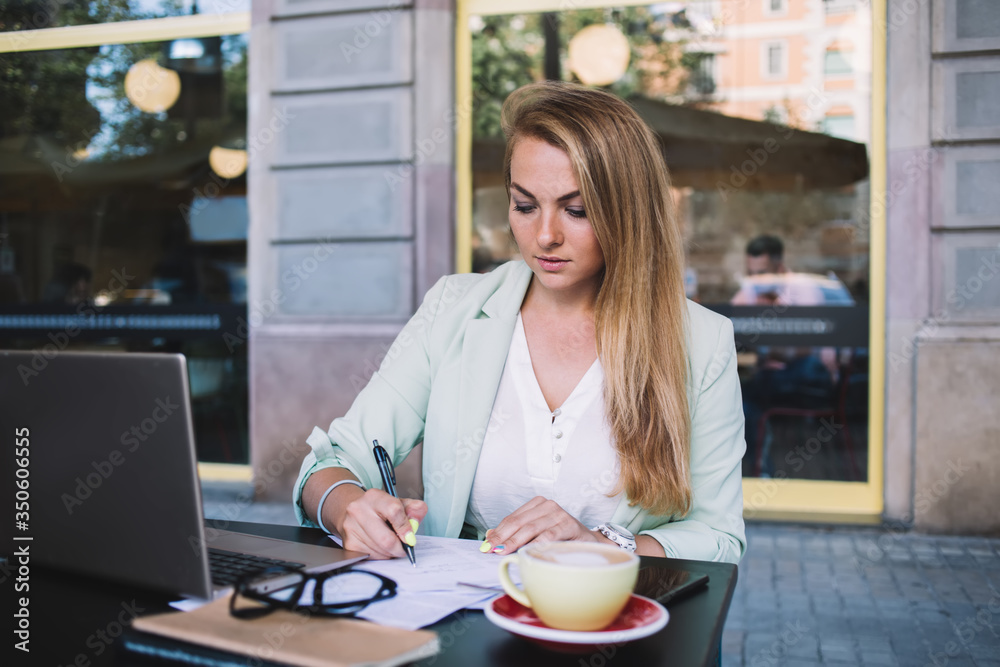 Serious woman taking notes using laptop Serious woman taking notes using laptop