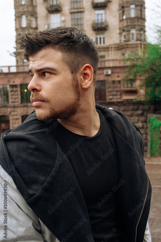 Portrait of a young man walking around the city. Brunette, beard. Cheerful, beautiful smile. Portrait of a young man walking around the city. Brunette, beard. Cheerful, beautiful smile.