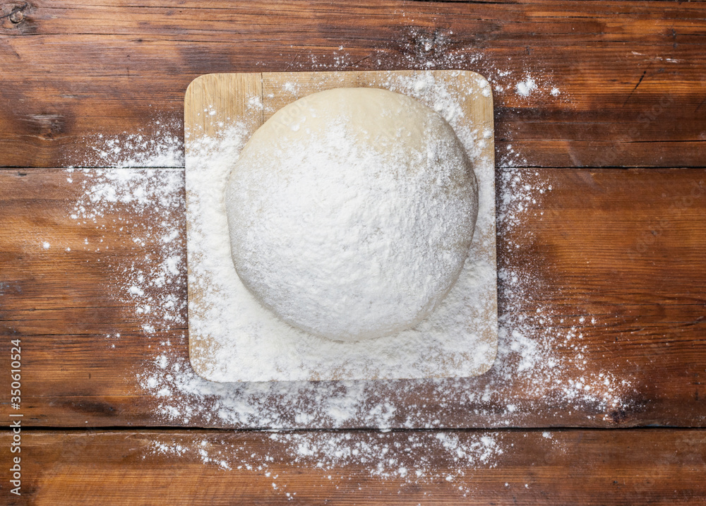 Ball of pizza dough on a rustic wooden background with dusting of flour Ball of pizza dough on a rustic wooden background with dusting of flour