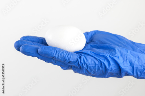 egg in the scientist's hand, against white wall background