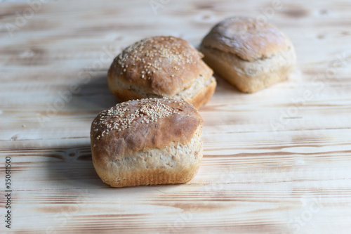 Fresh baked bread with sesame seeds on wooden table