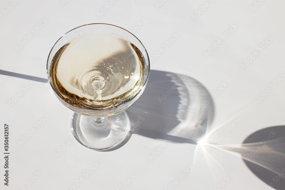 Sparkling wine in a glass on the white table in natural sunlight
