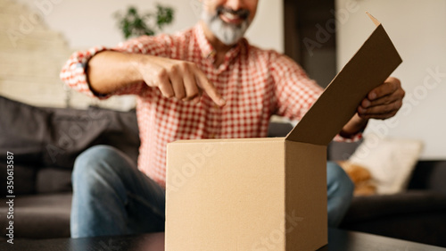 Mężczyzna otwierający pudełko kartonowe w domu photo