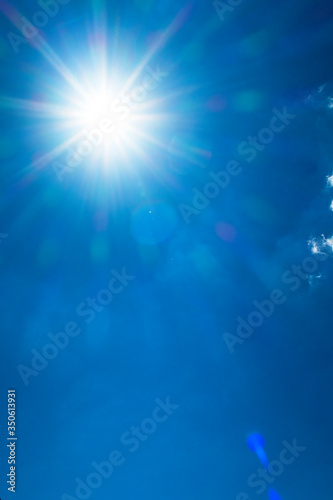 Shining sun with bokeh light & sunlight ray flares on beautiful sunny blue sky background in tropical summer or spring midday at daylight sunshine day, solar energy concept
