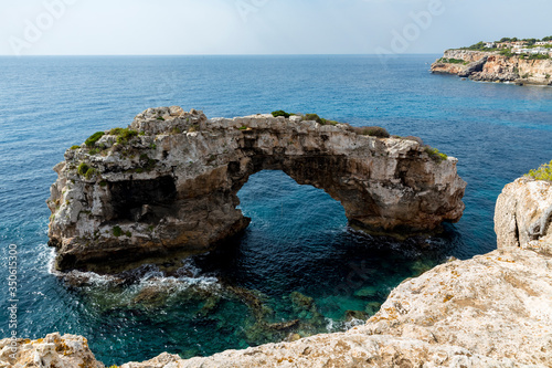 Es Spontás, imposing natural stone arch nestled in the sea near the coast. Santanyi, Mallorca Spain