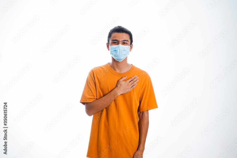 An Asian young man isolated on white background with casual entire and wearing a face mask. Hand gesture stop, sick, respect. during corona virus 