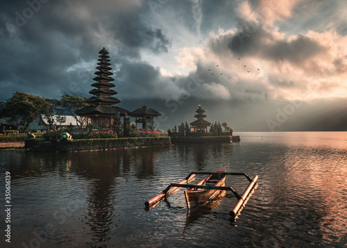 Ancient temple of Pura Ulun Danu Bratan with traditional boat on Bratan Lake at the sunrise in Bali