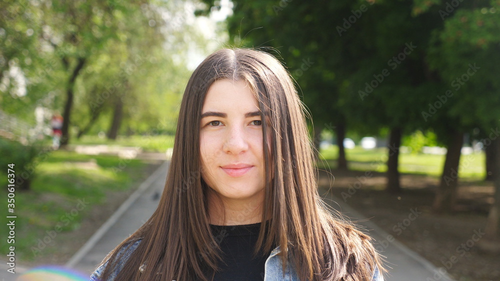 Naklejka premium Portrait of young happy woman standing at city street with positive emotions and feelings on his face. Beautiful girl looking and smiling into camera. Close up