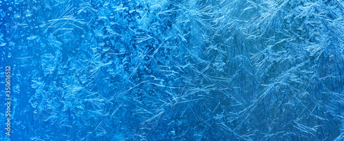Winter background. Abstract pattern blue frozen window on transparent glass