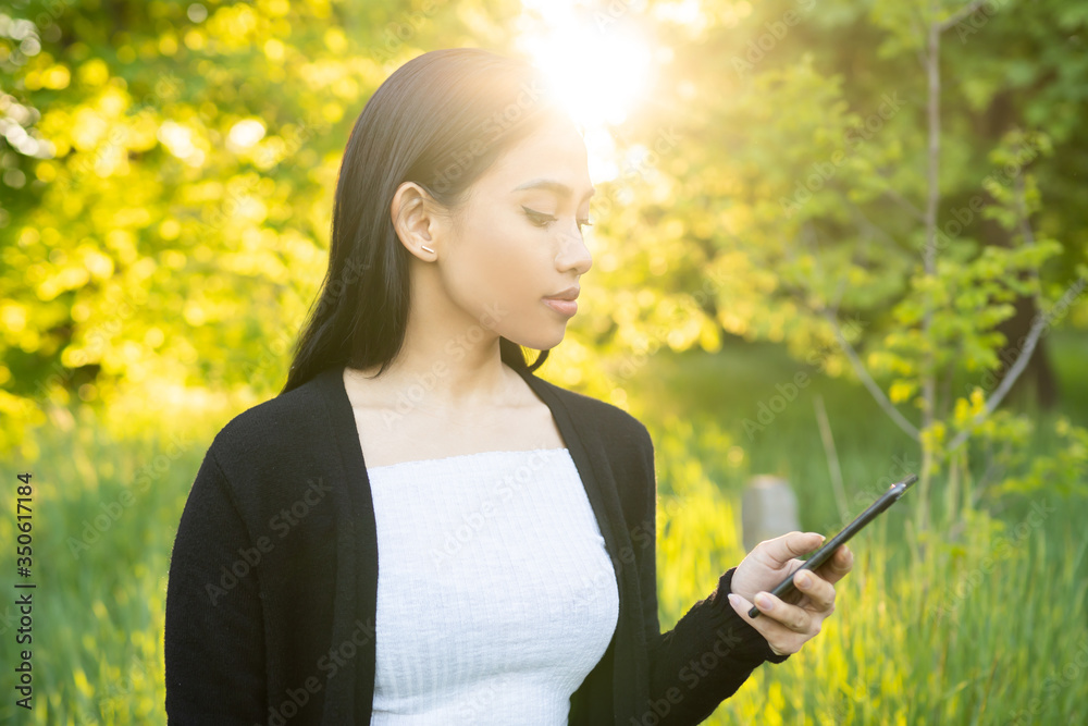 Woman using mobile phone outdoor with sunlight background. Woman using mobile phone outdoor with sunlight background.