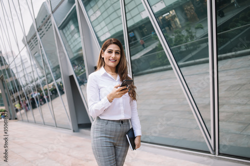 Smiling female surfing mobile in megapolis