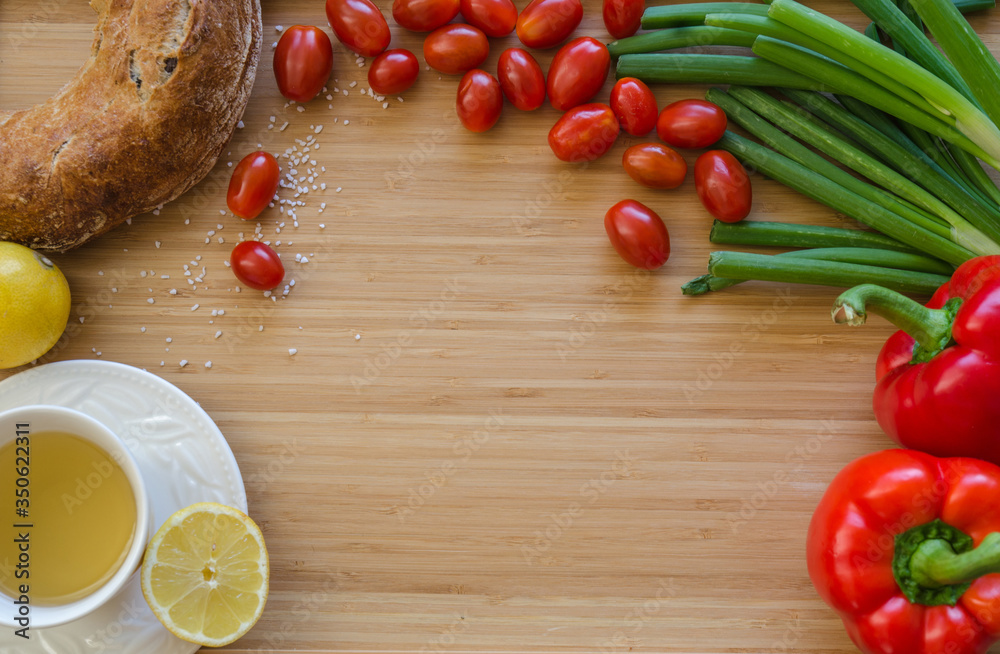 Cherry tomatoes, onions, bread, tea, lemon, peppers, arranged in a circle on a bamboo sheet. Healthy breakfast ingredients on the table. Kitchen composition before cooking, preparation. Cherry tomatoes, onions, bread, tea, lemon, peppers, arranged in a circle on a bamboo sheet. Healthy breakfast ingredients on the table. Kitchen composition before cooking, preparation.