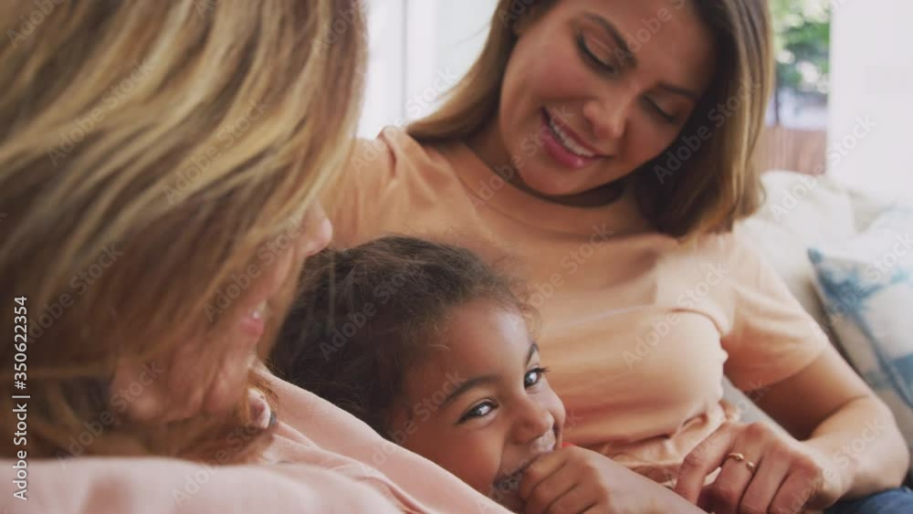 Multi-generation female Hispanic family relaxing on sofa at home talking and laughing together - shot in slow motion Multi-generation female Hispanic family relaxing on sofa at home talking and laughing together - shot in slow motion