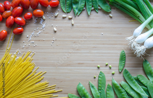 Cherry tomatoes, onions, Italian pasta, green beans, arranged in a circle on a bamboo sheet. Healthy ingredients in the atlas. Kitchen composition before cooking, preparation.