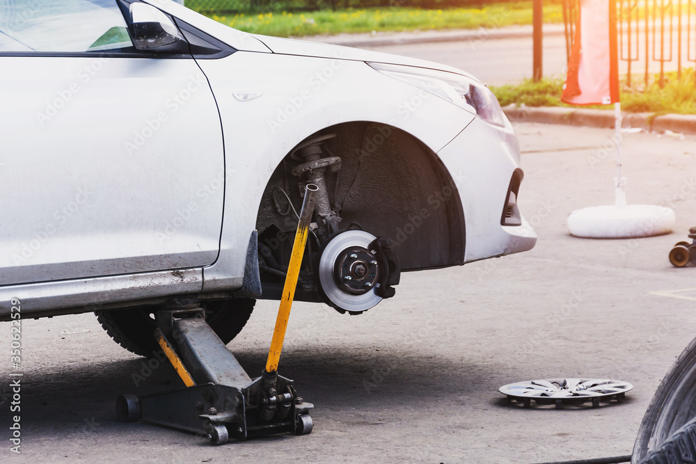 Replacing tires on wheels, a car without a front wheel on a jack, express service maintenance.