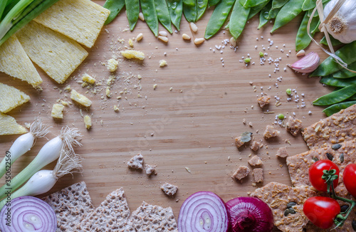 Green peas, onions, fitness bread, pine nuts, arranged in a circle on a bamboo sheet. Healthy breakfast ingredients on the table. Kitchen composition before cooking, preparation.