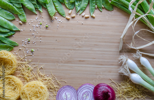 Green peas, onions, soup pasta, pine nuts, arranged in a circle on a bamboo sheet. Kitchen composition before cooking, preparation.