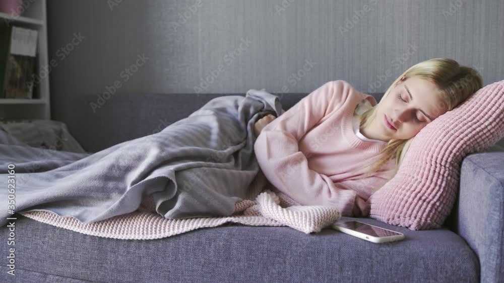 Young beautiful woman been woken up by phone call. Woman napping on couch in living room Young beautiful woman been woken up by phone call. Woman napping on couch in living room