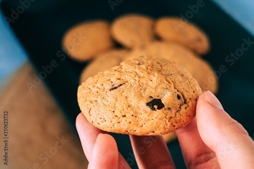 Homemade chocolate cookies on black plate and blue background.