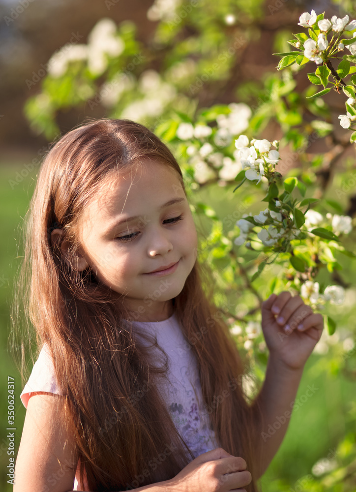 little girl with long hair near a flowering tree little girl with long hair near a flowering tree