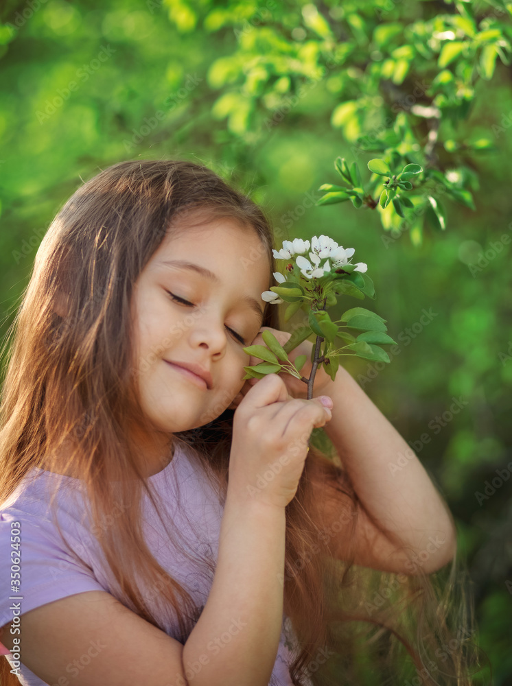 little girl with long hair near a flowering tree in nature little girl with long hair near a flowering tree in nature