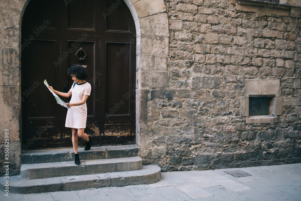 Black traveler reading map on steps of aged building