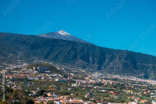 Landscape of the city of Puerto de La Cruz and the Teide volcano on a Sunny day under a blue sky. Tropical island with a volcano near the city © Евгений Симдянкин