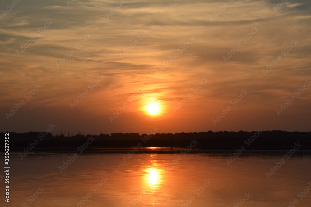 Beautiful sunset on the Volga river. 
The sun is reflected in the river. Russia. Golden background.