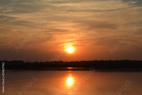 Beautiful sunset on the Volga river. The sun is reflected in the river. Russia. Golden background.
