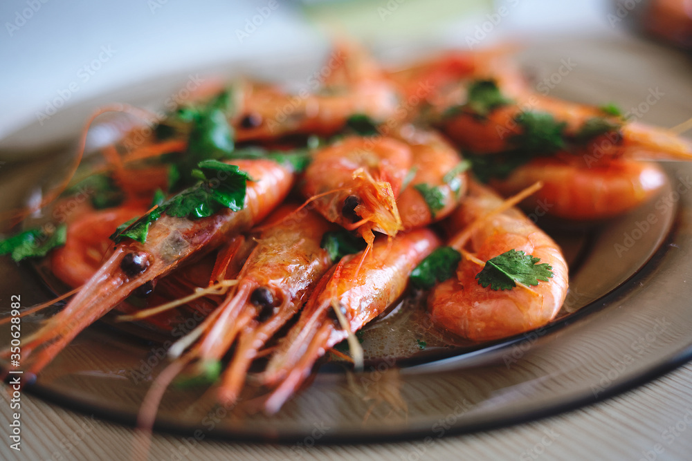 Delicious prawns with coriander in a plate on the table. Fresh seafood dish close-up Delicious prawns with coriander in a plate on the table. Fresh seafood dish close-up