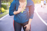 Woman suffering from painful chest or Symptoms of heart disease while running at public park.