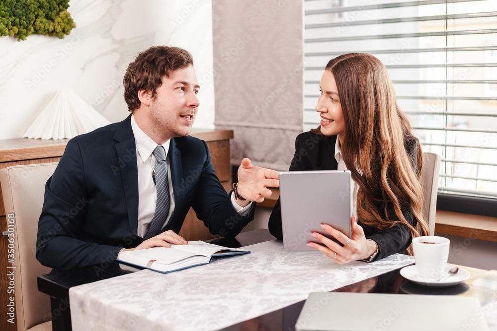 Young business woman and businessman are using tablet and document, talking about finances. Young business woman and businessman are using tablet and document, talking about finances.