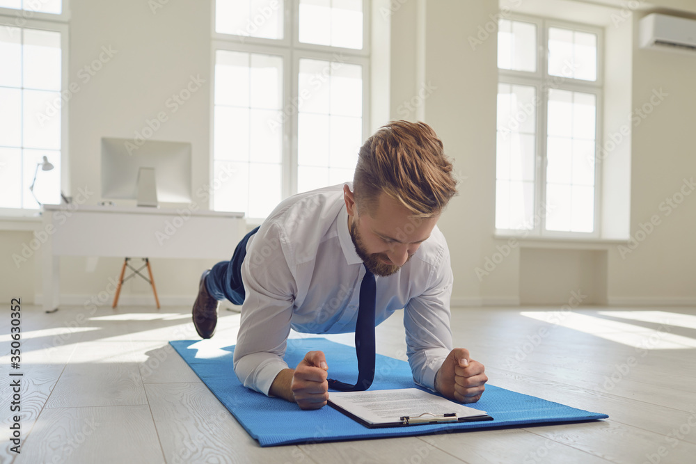 Businessman doing abs strap exercises while lying in the office. Businessman doing abs strap exercises while lying in the office.