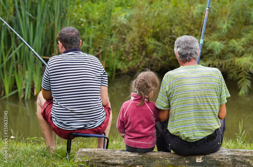 fish on the river back view grandfather and dad