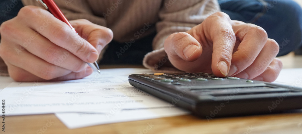 close-up of hand with pen, calculator and documents close-up of hand with pen, calculator and documents
