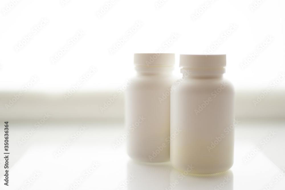two white plastic pill bottles isolated on a white background two white plastic pill bottles isolated on a white background