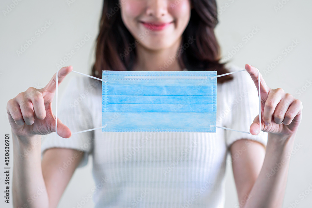 young beautiful asian woman showing how to wear a medical mask or