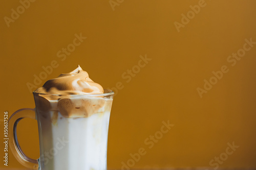 quarantine trend drink Korean dalgona coffee. Whipped milk cold shaked coffee. Cappuccino latte sweet cream delicious hyster. Yellow background place for text banner. foam close-up photo