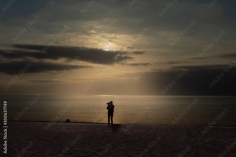 man in the beach in sunrise with clouds and sun man in the beach in sunrise with clouds and sun