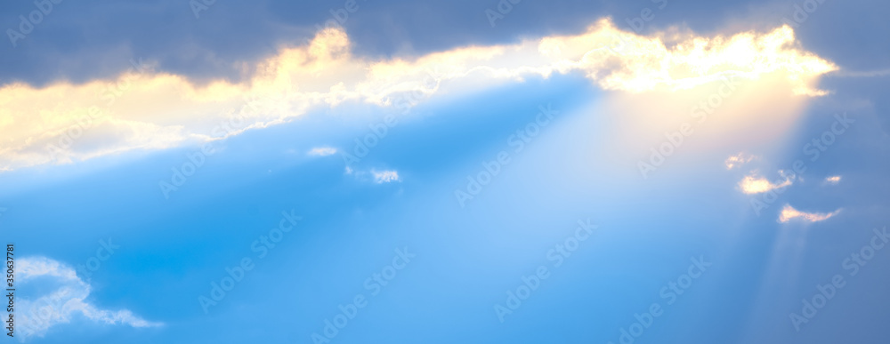 The sun's rays break through the blue clouds. The background of the sky.