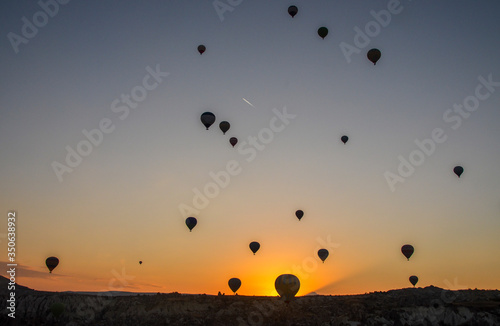 The sunrise in the mountains with Hot air balloons flying over Cappadocia red valley in the sky. Travel to Goreme, Turkey
