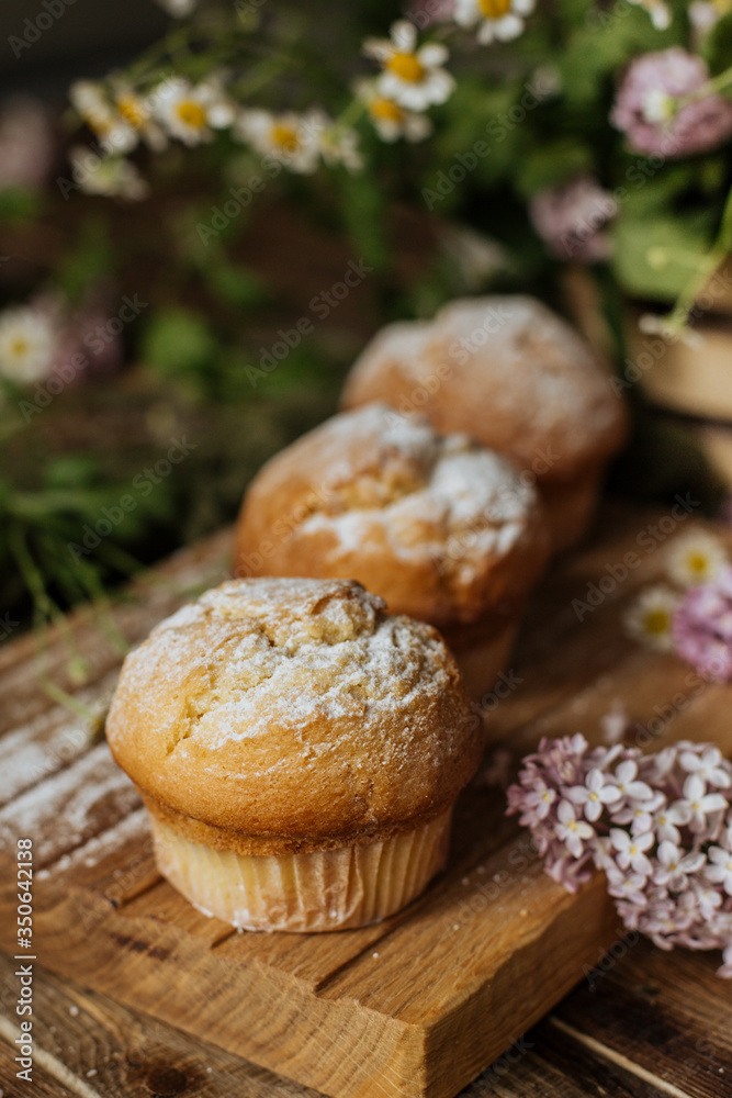 On the table among the lilac branches are vanilla cupcakes