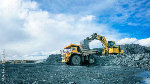 Work of trucks and the excavator in an open pit photo