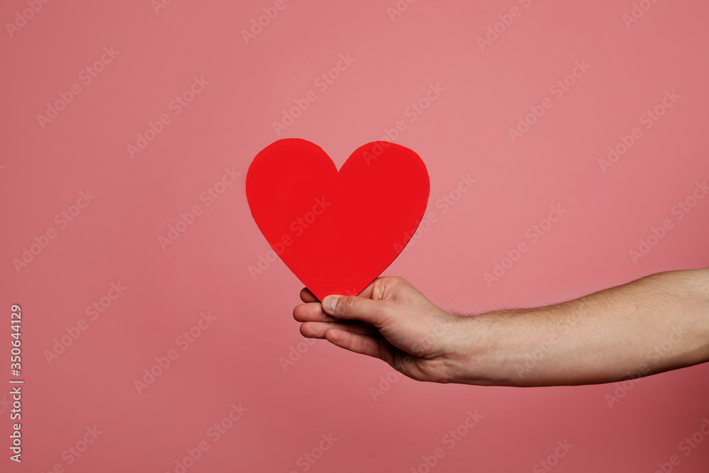 St. Valentine. Close-up photo of a red heart-shaped card in a man's hand. St. Valentine. Close-up photo of a red heart-shaped card in a man's hand.