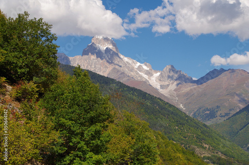 Scenic autumn landscape in the mountains of the Caucasus. Snowcapped peak of the Ushba Mountain. Nature and travel. Georgia, Svaneti region