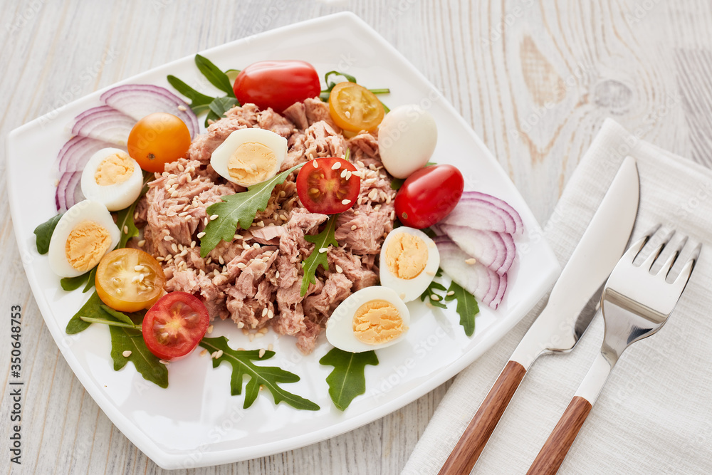 Tuna salad with arugula and tomatoes on light wooden background. Healthy food, seafood menu, Tuna salad with arugula and tomatoes on light wooden background. Healthy food, seafood menu,