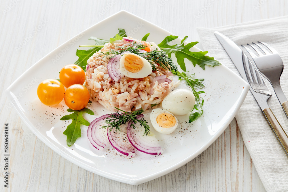 Tuna salad with rice, arugula and tomatoes on light wooden background. Healthy food, seafood menu, Tuna salad with rice, arugula and tomatoes on light wooden background. Healthy food, seafood menu,
