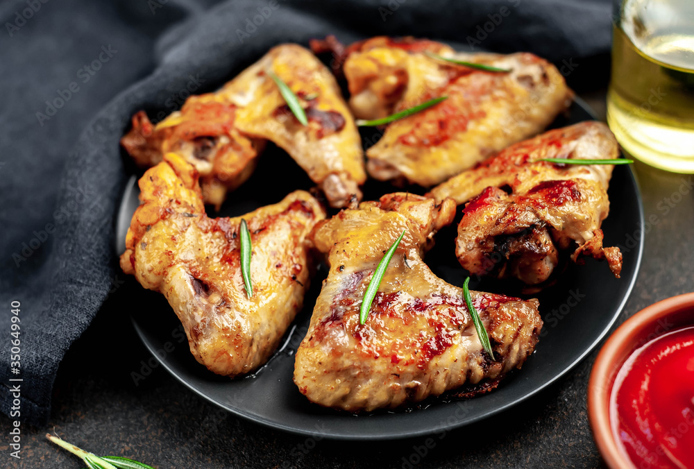 Grilled chicken wings on a plate with spices on a stone background Grilled chicken wings on a plate with spices on a stone background