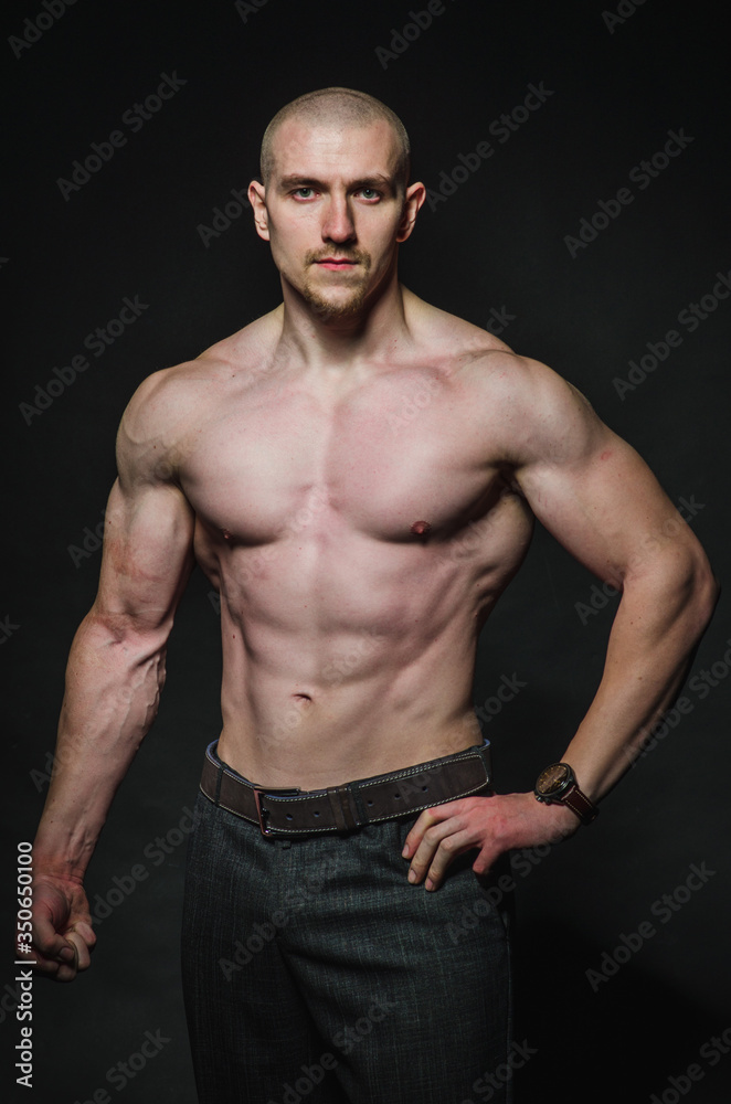 Fototapeta premium Sporty sexy man stands Topless on a dark background. Sports, beauty